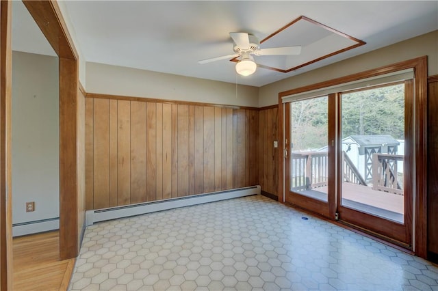 spare room with ceiling fan, wood walls, and a baseboard radiator