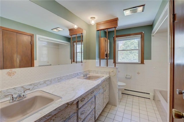 full bathroom featuring toilet, a baseboard heating unit, a sink, and tile patterned flooring