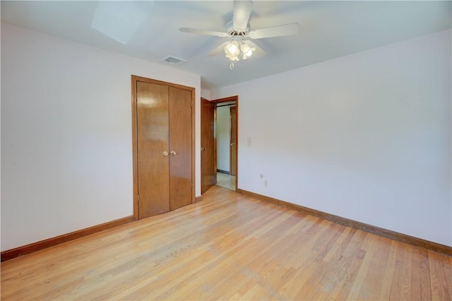 spare room with baseboards, a ceiling fan, light wood-style flooring, and visible vents