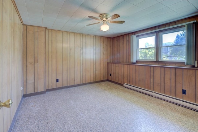 empty room with baseboards, wooden walls, ceiling fan, and baseboard heating