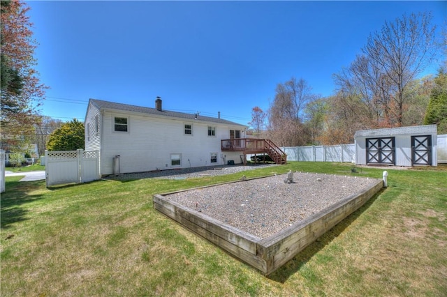 view of yard with a storage unit, a wooden deck, stairway, a fenced backyard, and an outbuilding