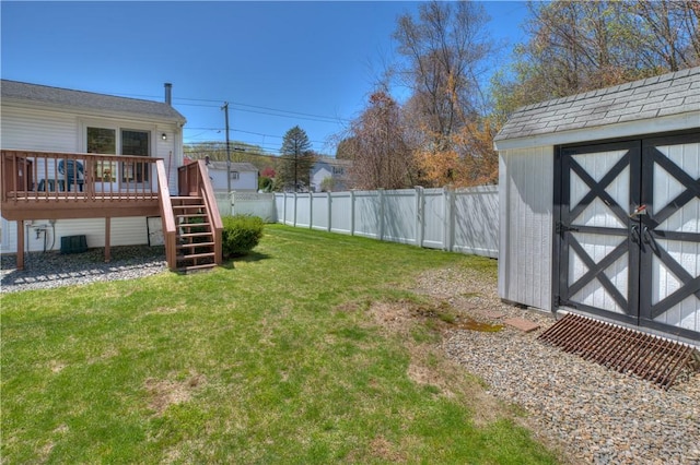view of yard with a wooden deck, a fenced backyard, a storage shed, central air condition unit, and an outbuilding
