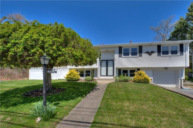 raised ranch featuring a garage, fence, and a front yard