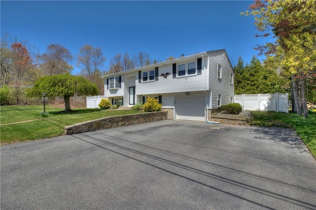 split foyer home featuring fence, an attached garage, driveway, and a front yard