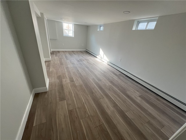 basement featuring baseboards, a baseboard heating unit, and wood finished floors
