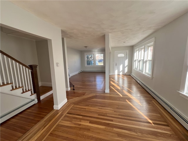 entrance foyer featuring baseboards, a baseboard heating unit, wood finished floors, and stairway