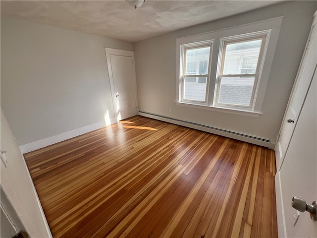 empty room featuring a baseboard heating unit and hardwood / wood-style floors