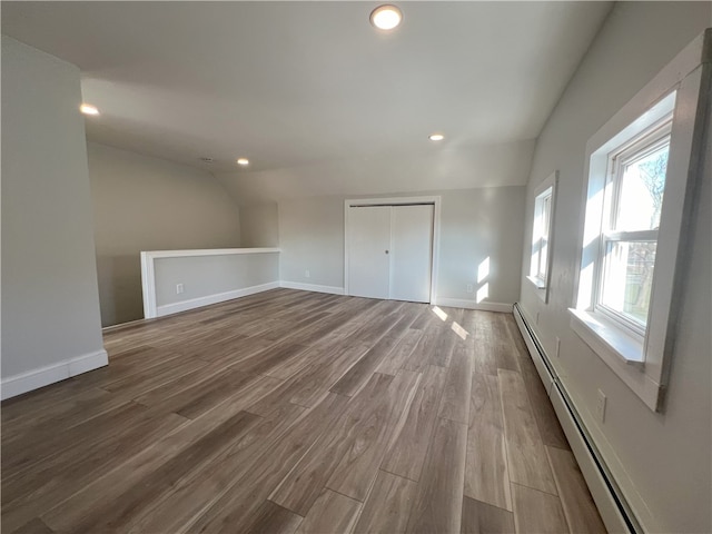 spare room featuring baseboard heating, wood finished floors, baseboards, lofted ceiling, and recessed lighting