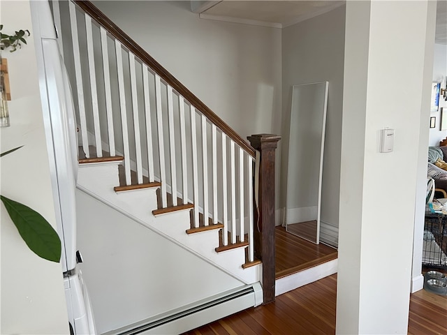 stairway featuring wood finished floors and a baseboard heating unit