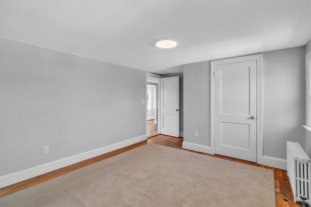 32 Summer St, Woonsocket, RI 02895 - unfurnished bedroom featuring baseboards, radiator heating unit, and wood finished floors