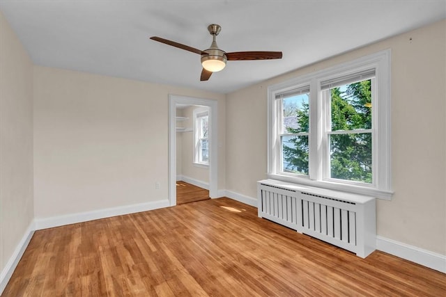 32 Summer St, Woonsocket, RI 02895 - empty room featuring light wood-style floors, baseboards, ceiling fan, and radiator heating unit