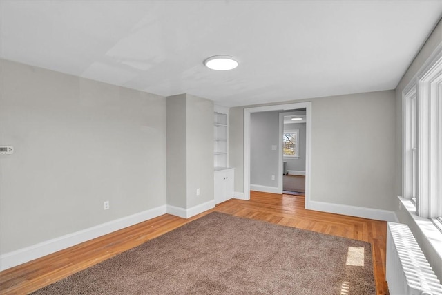 32 Summer St, Woonsocket, RI 02895 - unfurnished room with baseboards, radiator heating unit, built in shelves, and light wood-type flooring