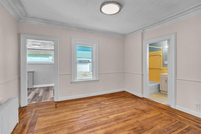 32 Summer St, Woonsocket, RI 02895 - unfurnished bedroom featuring light wood-style floors, crown molding, baseboards, radiator heating unit, and ensuite bath