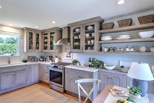 kitchen featuring a sink, gas stove, wall chimney range hood, and light countertops
