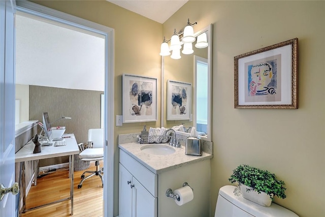 half bath featuring toilet, wood finished floors, and vanity