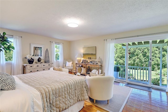 bedroom with access to outside, a textured ceiling, and wood finished floors