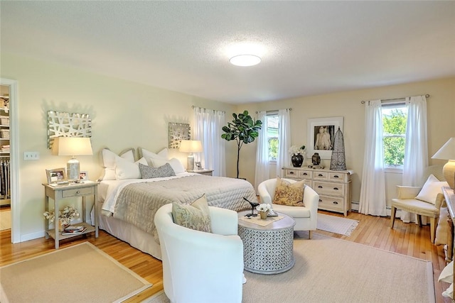 bedroom with light wood-style floors and a baseboard heating unit