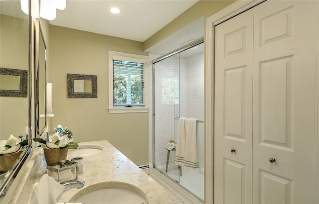 bathroom with a sink, double vanity, recessed lighting, a closet, and a stall shower