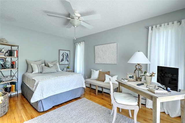 bedroom featuring a baseboard heating unit, a textured ceiling, and wood finished floors