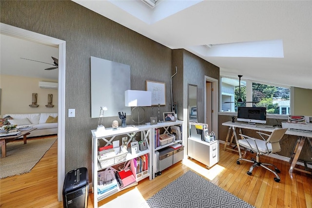 office space featuring light wood-style floors, a wall mounted air conditioner, and wallpapered walls