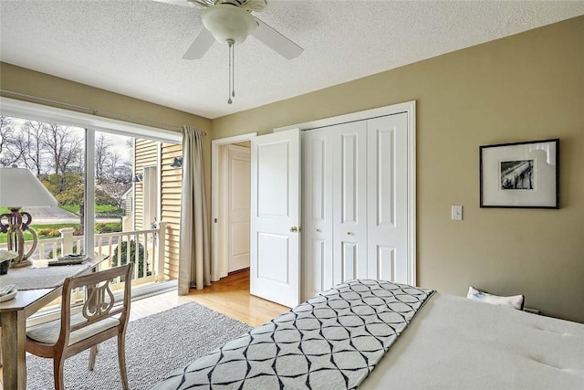bedroom with a closet, access to exterior, ceiling fan, light wood-type flooring, and a textured ceiling