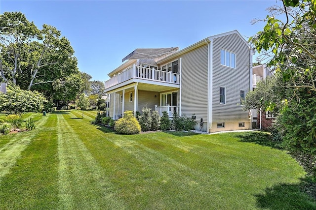 rear view of house featuring a lawn and a balcony