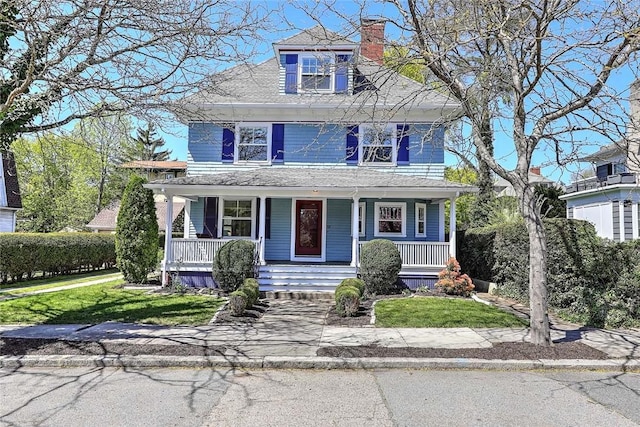 view of front of property with a front yard, covered porch, and a chimney
