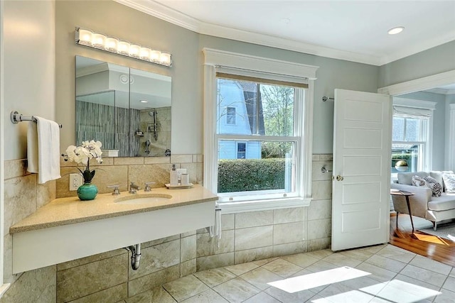 full bathroom with a sink, ornamental molding, tiled shower, and a healthy amount of sunlight