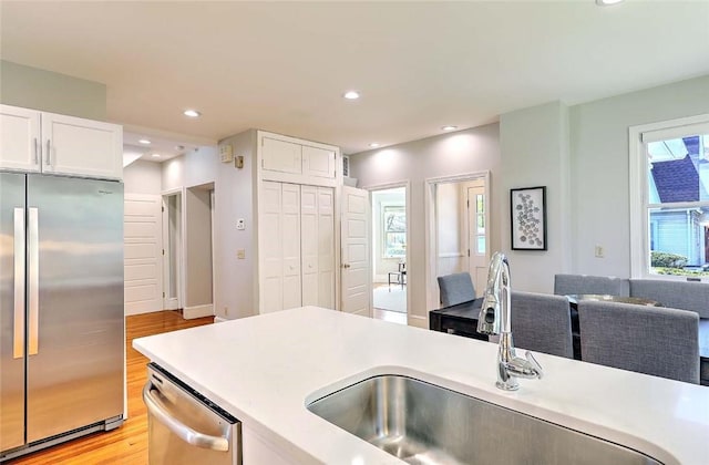 kitchen featuring a sink, light countertops, stainless steel appliances, and light wood-style flooring