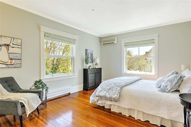 bedroom featuring hardwood / wood-style floors, a wall unit AC, baseboard heating, and multiple windows