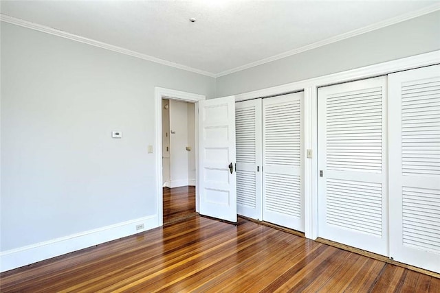 unfurnished bedroom with crown molding, multiple closets, baseboards, and dark wood finished floors
