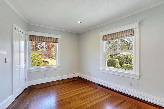 spare room featuring wood-type flooring, baseboards, a baseboard heating unit, and a healthy amount of sunlight