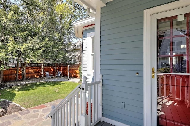 view of exterior entry featuring a yard and fence