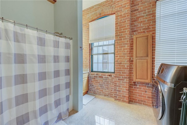 full bath featuring brick wall, washer / dryer, and curtained shower