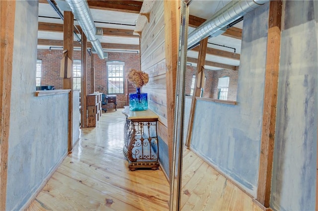 hallway with wood finished floors and brick wall