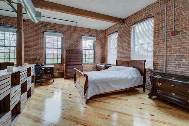 bedroom with beamed ceiling, light wood-type flooring, and brick wall