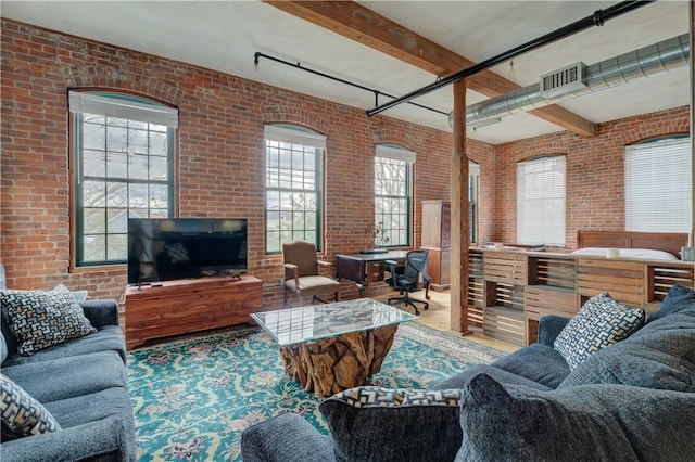 living room with beamed ceiling, brick wall, and plenty of natural light