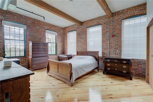 bedroom featuring brick wall, hardwood / wood-style floors, and beamed ceiling