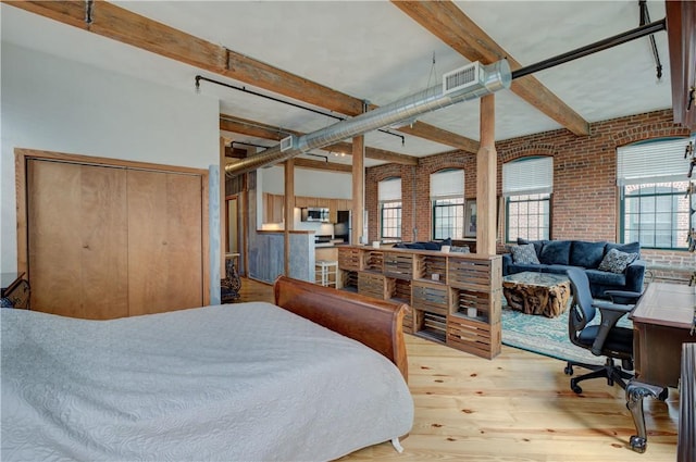 bedroom featuring brick wall, beamed ceiling, wood finished floors, and visible vents