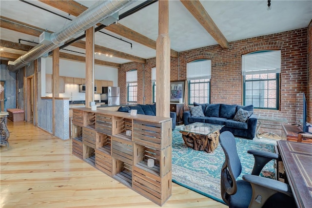 living room featuring brick wall, beam ceiling, and hardwood / wood-style flooring
