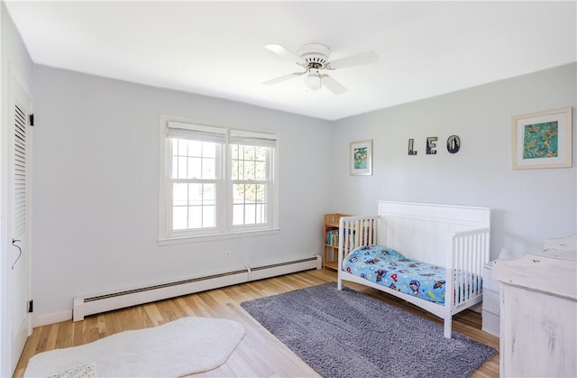 bedroom featuring a ceiling fan, wood finished floors, and baseboard heating