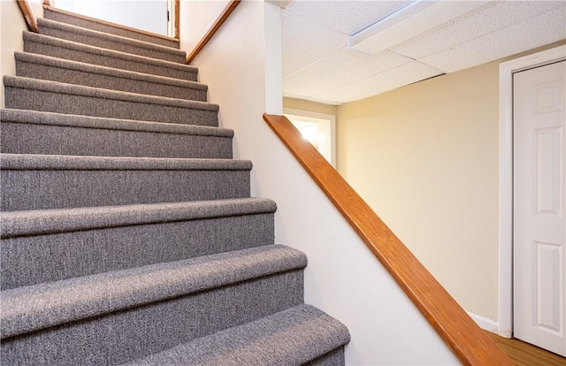 staircase featuring a paneled ceiling and wood finished floors