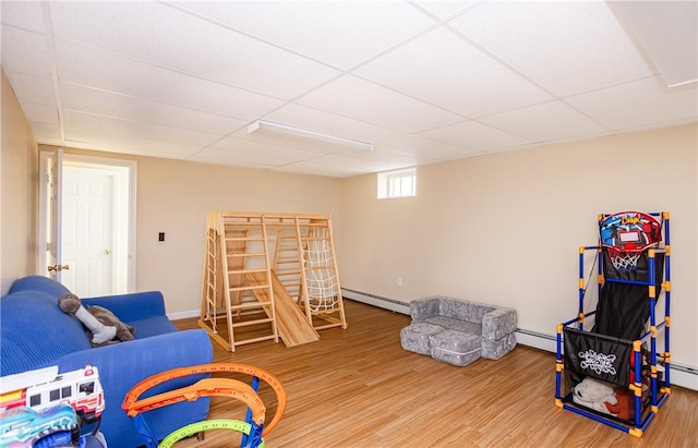interior space with a paneled ceiling, baseboards, a baseboard heating unit, and wood finished floors