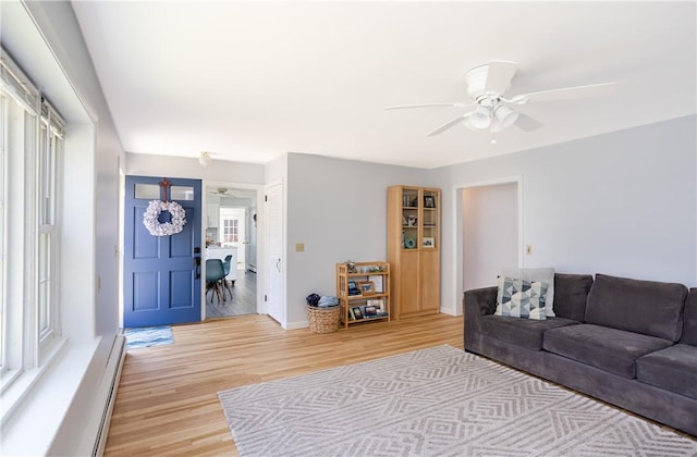 living room featuring baseboards, ceiling fan, baseboard heating, and light wood finished floors