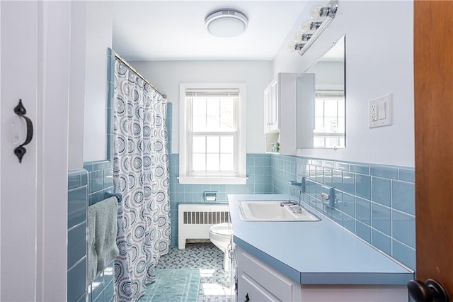 bathroom with vanity, wainscoting, toilet, tile walls, and radiator heating unit