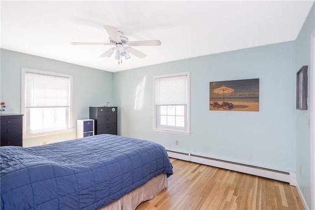 bedroom with baseboards, a ceiling fan, a baseboard heating unit, and light wood finished floors