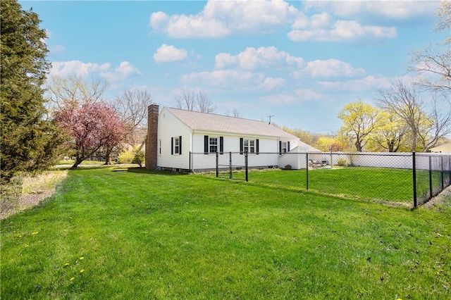 rear view of house with fence, a chimney, and a yard