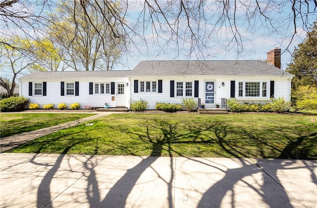 single story home with entry steps, a chimney, and a front yard
