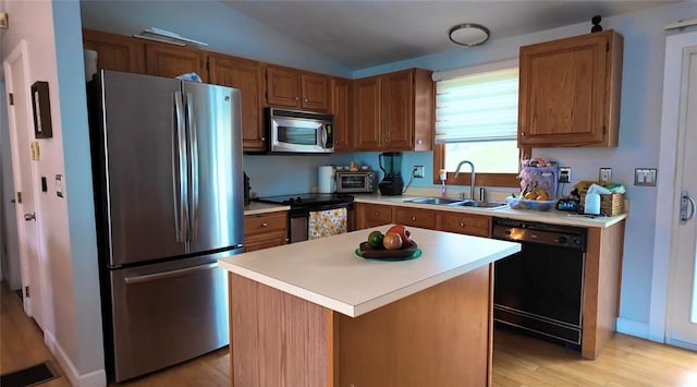 kitchen featuring light countertops, appliances with stainless steel finishes, a sink, and light wood finished floors