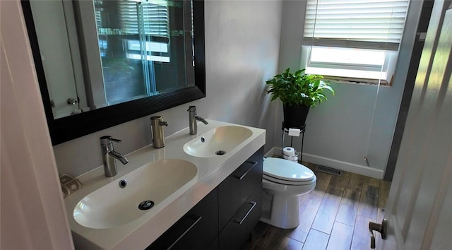 bathroom featuring plenty of natural light, a sink, visible vents, and toilet